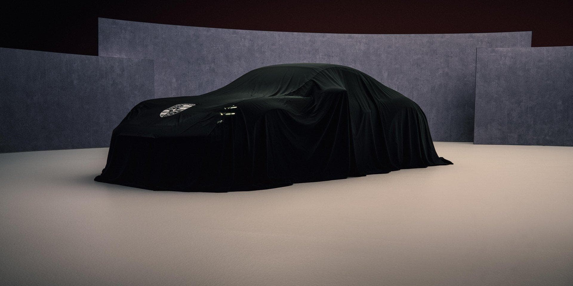 Covered Porsche Mission S concept showing its low mid-engine supercar silhouette and possible roof-mounted air intake.